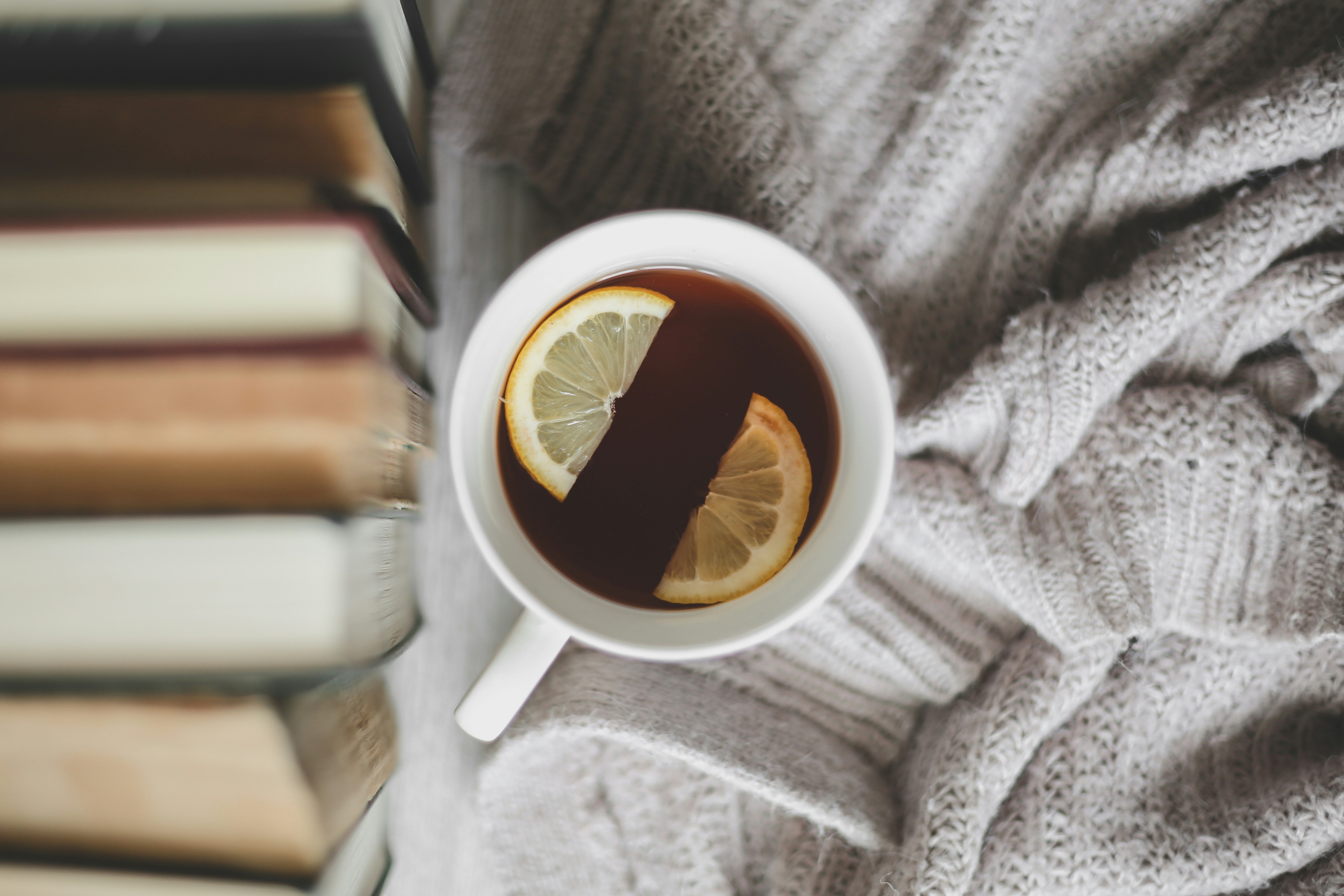 Cup of tea with lemon slices on cozy blanket