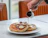 A colorful plate with mini hotcakes topped with Nutella, banana slices, and chopped nuts, styled with soft natural light.