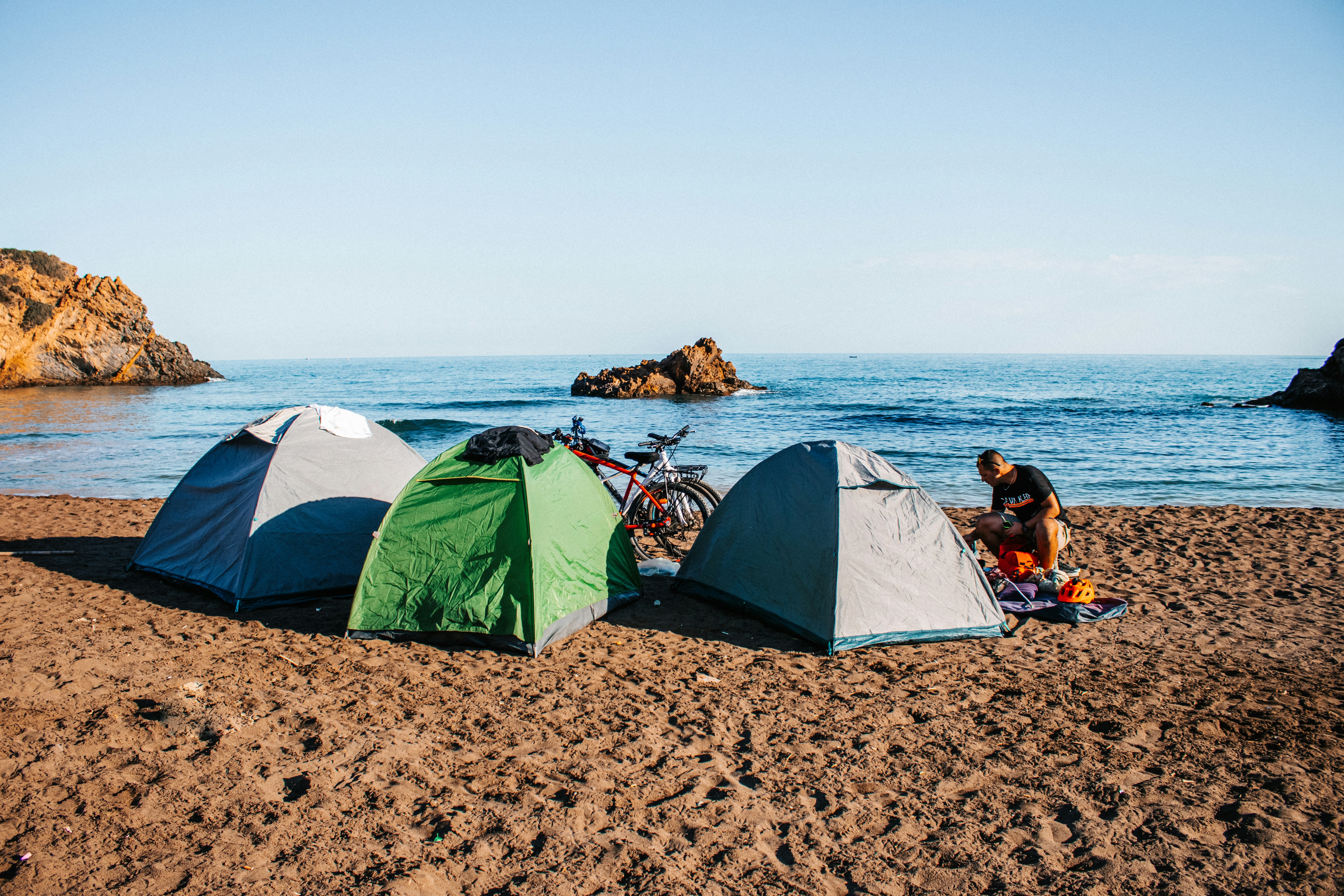 a person sitting next to a couple of tents on a beach