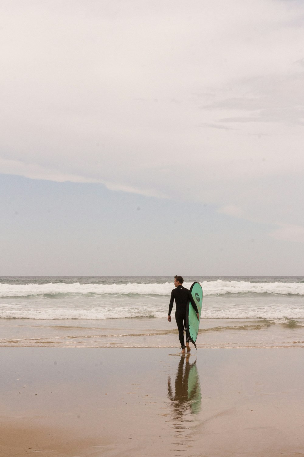 a couple of men carrying surfboards on a beach