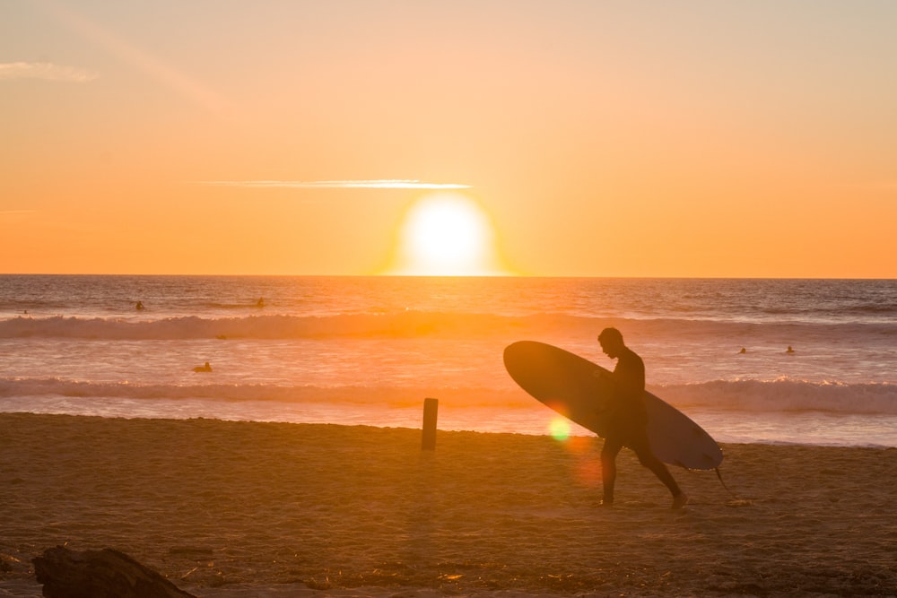 a person carrying a surfboard on the beach