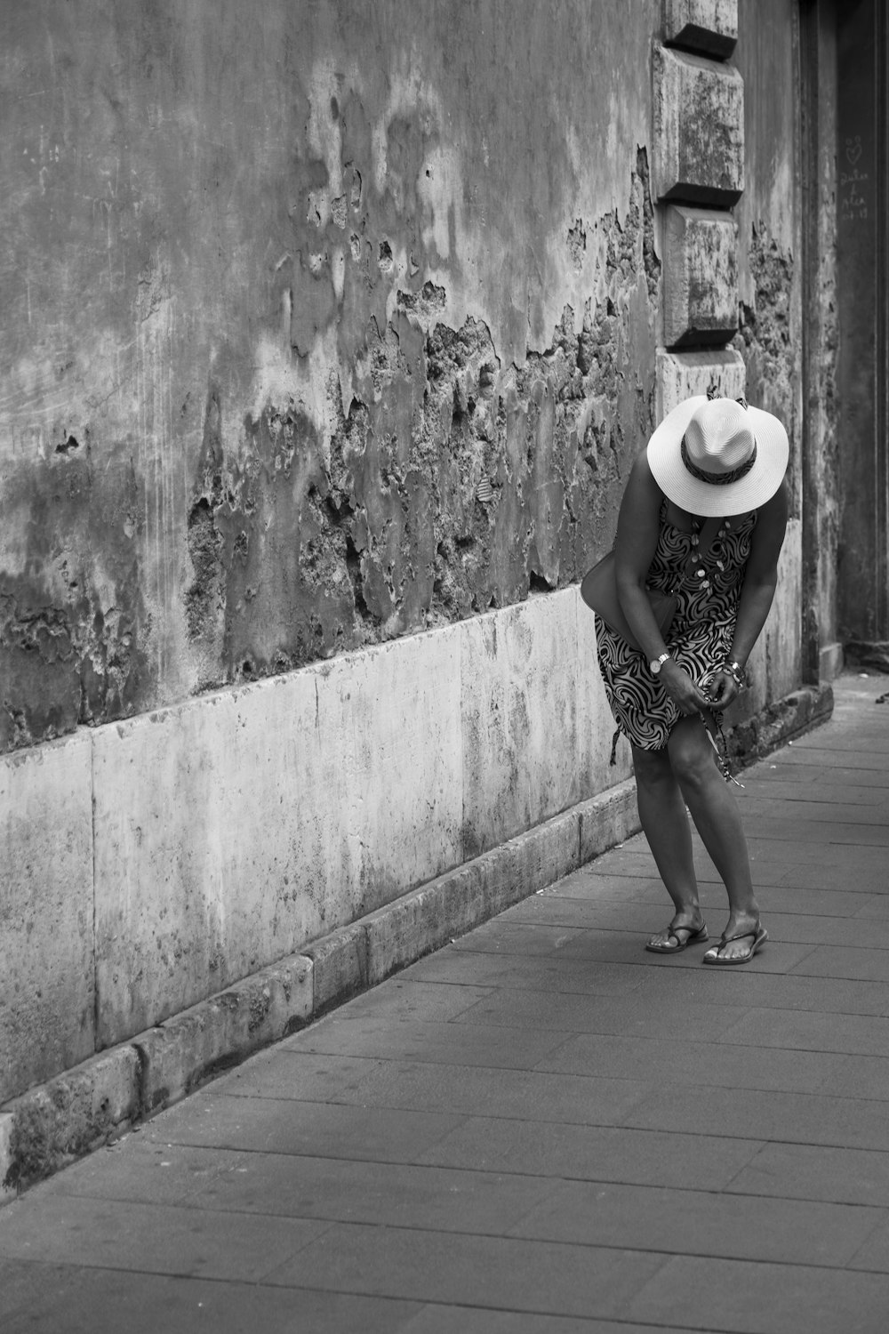 a woman in a hat looking at a wall