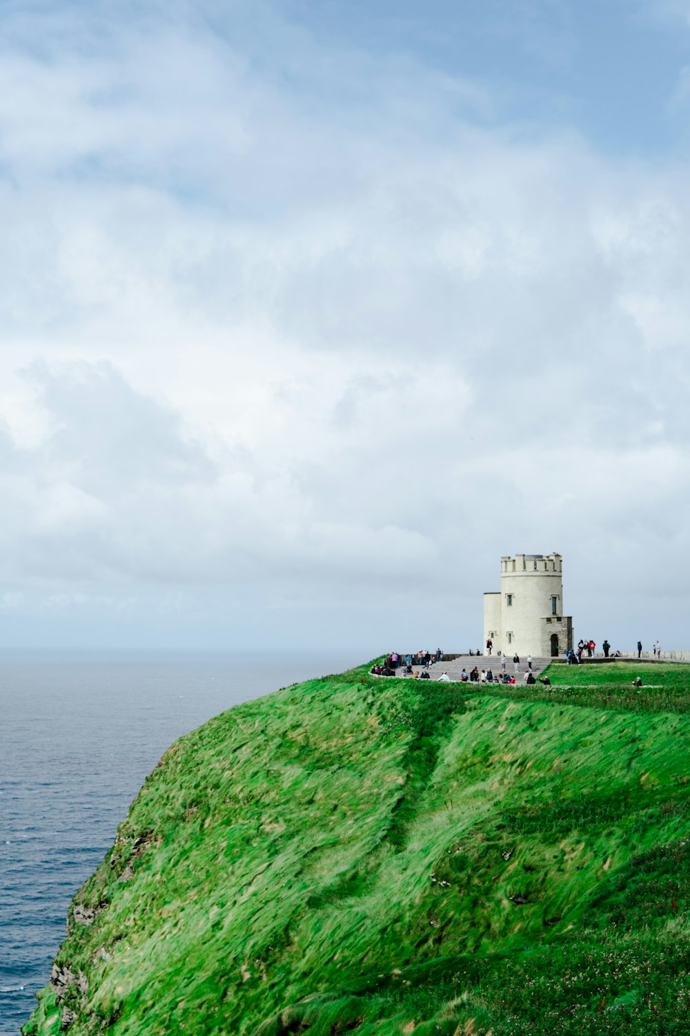 a stone tower on a hill by the water