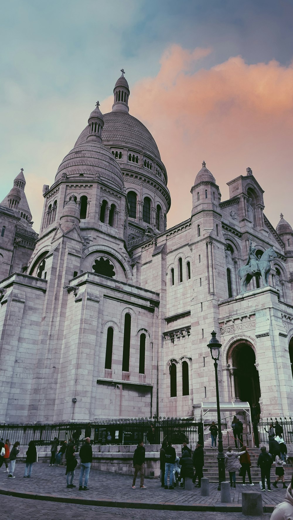 a large white building with a dome and statues on the roof with Sacré-Cœur, Paris in the background