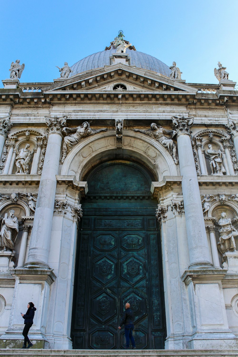 Un edificio con una gran puerta y estatuas en el techo