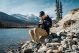 a man sitting on a rock by a lake
