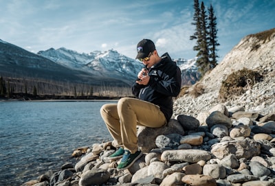 a man sitting on a rock by a lake