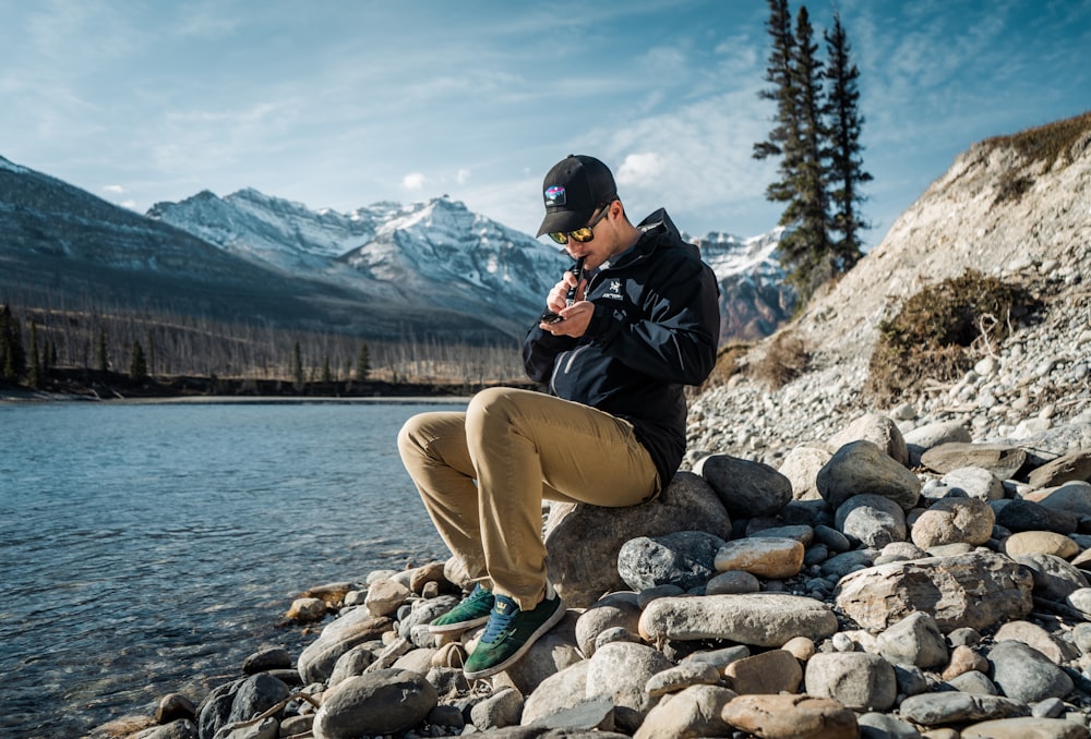 a man sitting on a rock by a lake