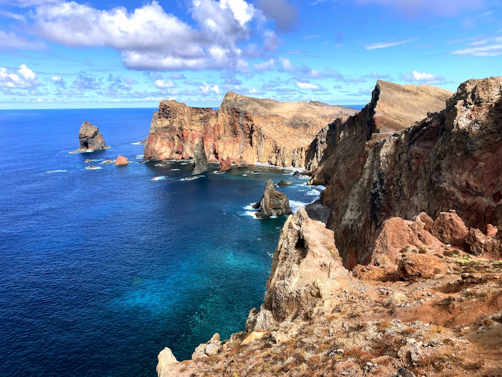 a rocky cliff next to a body of water