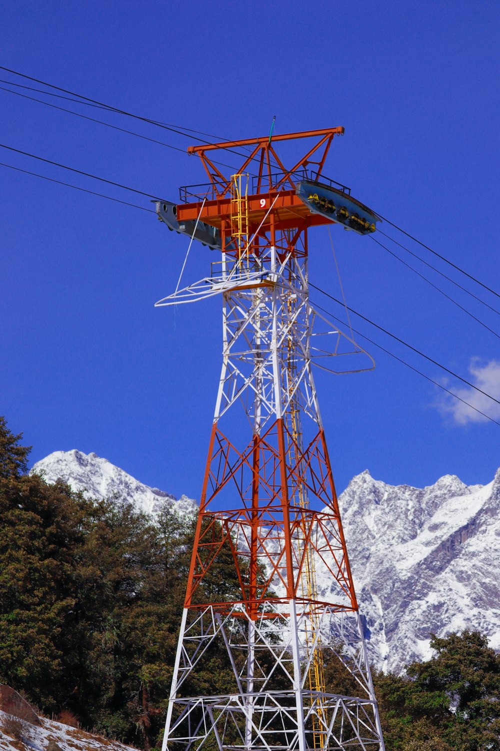 a tower with wires and a mountain in the background