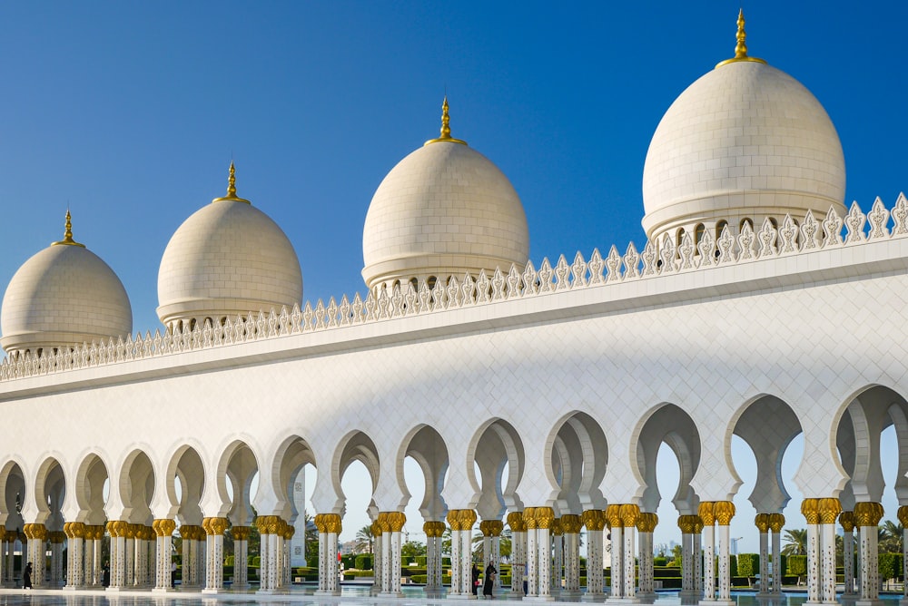 a large white building with domed roofs with Sheikh Zayed Mosque in the background