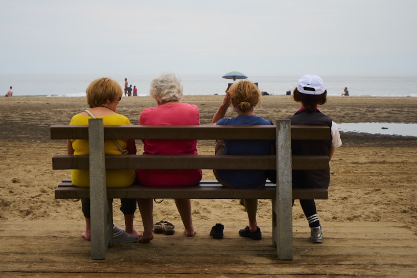 a group of people sitting on a bench at the beach