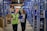 Smiling businesswoman holding a clipboard in a warehouse filled with industrial supplies.