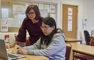 a woman showing a woman something on the laptop