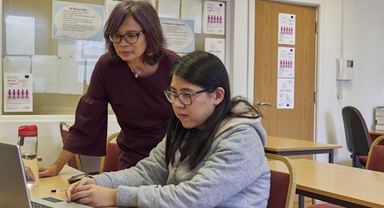 a woman showing a woman something on the laptop