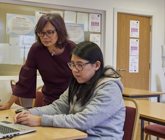 a woman showing a woman something on the laptop