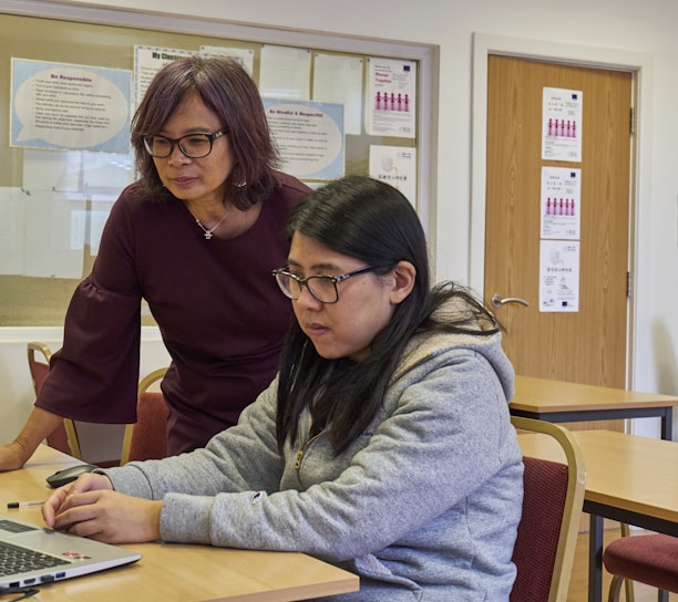 a woman showing a woman something on the laptop