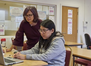 a woman showing a woman something on the laptop