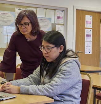 a woman showing a woman something on the laptop