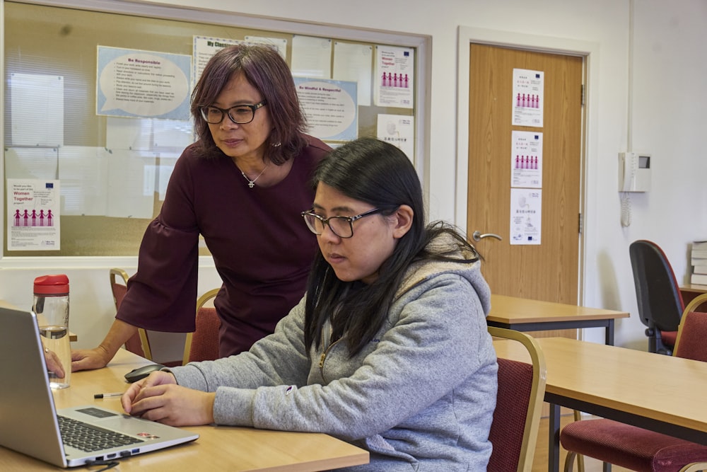 a woman showing a woman something on the laptop