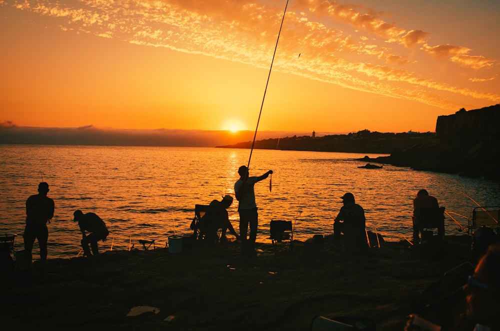 a group of people fishing at sunset