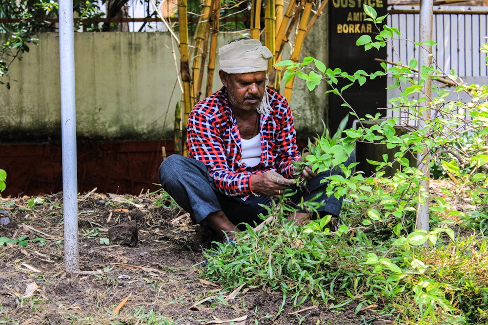 a man squatting in a garden