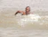 Close-up shot of an athlete swimming in open water, water splashing dramatically.