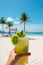 A close-up of vibrant sandals beside a refreshing tropical drink on a wooden deck.