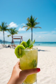 A close-up of vibrant sandals beside a refreshing tropical drink on a wooden deck.