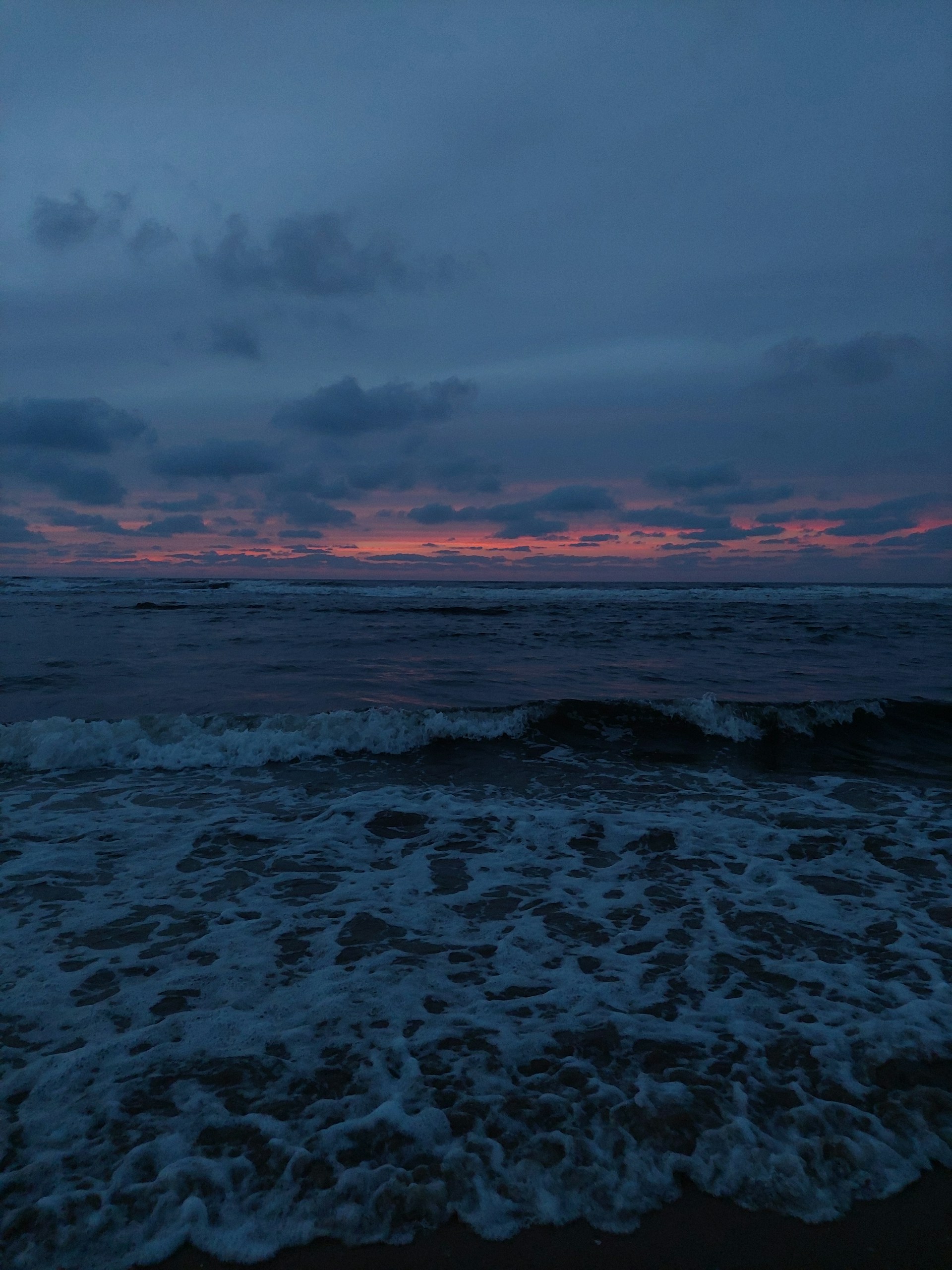 a beach with waves and a cloudy sky