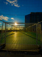 A dynamic shot of a soccer ball hitting the net during a sunset match.