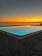 A serene sunset over the private pool with warm golden light reflecting on calm water.
