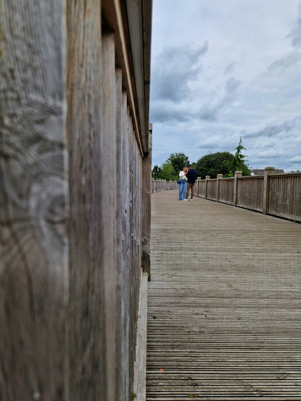 a couple walking on a wooden bridge