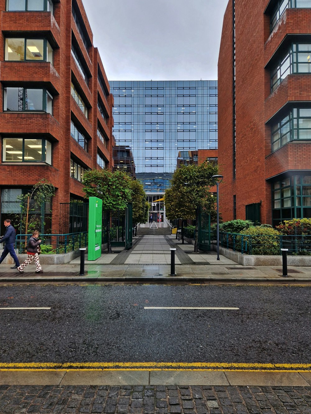 a couple of people walking on a sidewalk next to a street