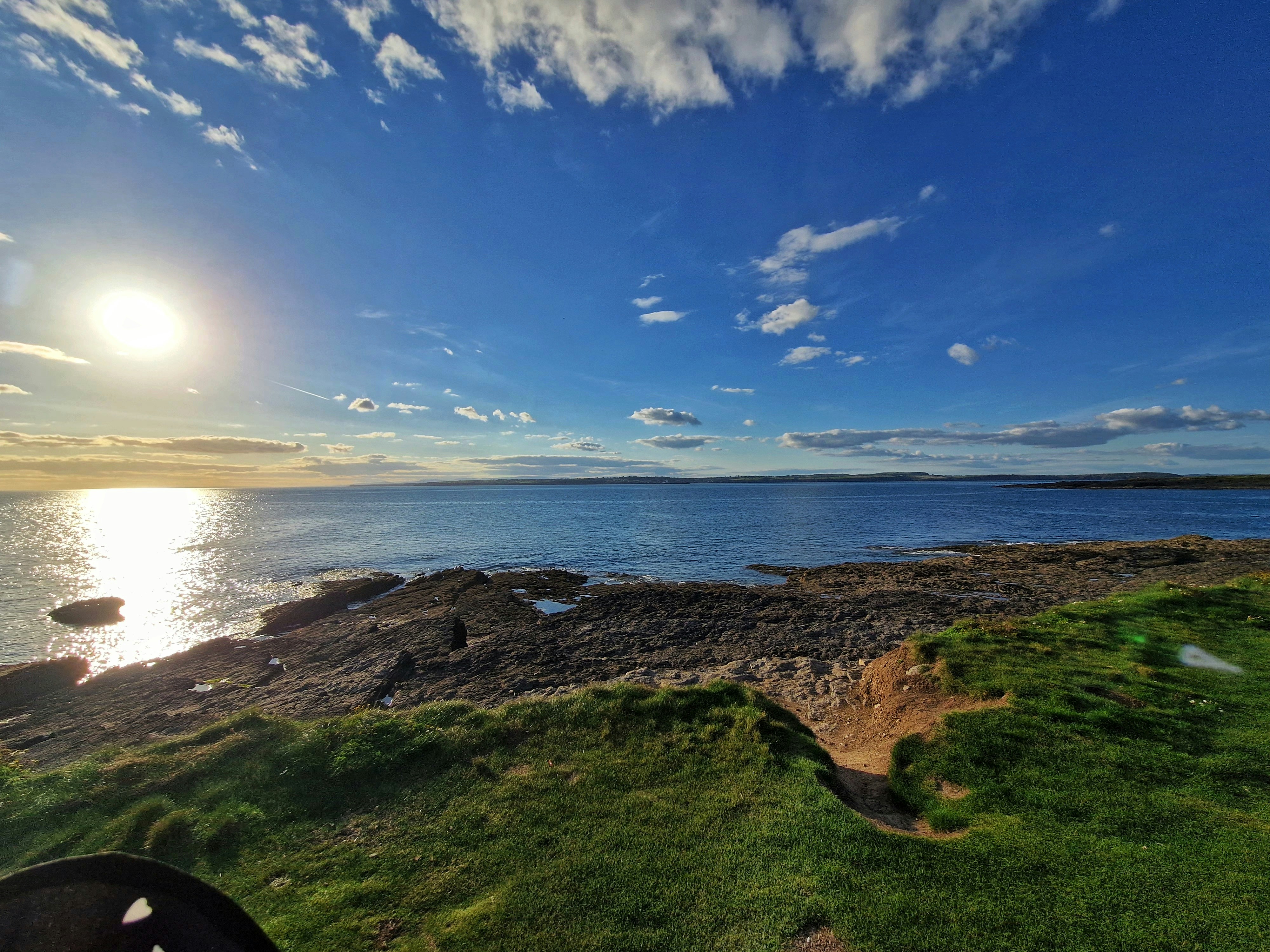 a body of water with grass and rocks on the side