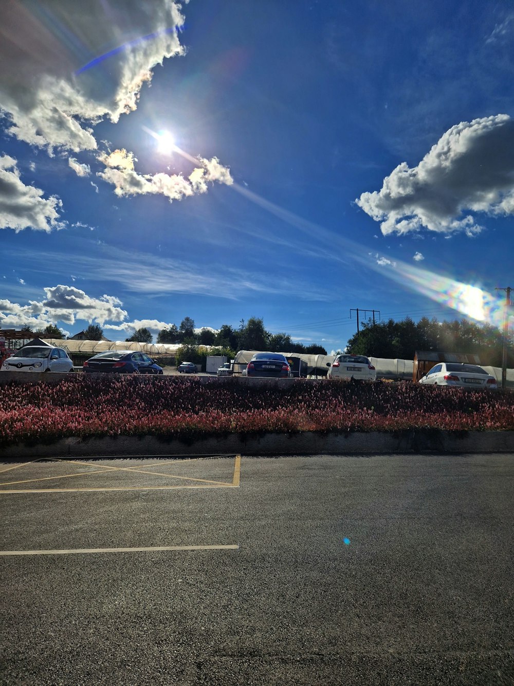 a parking lot with cars and a blue sky with clouds