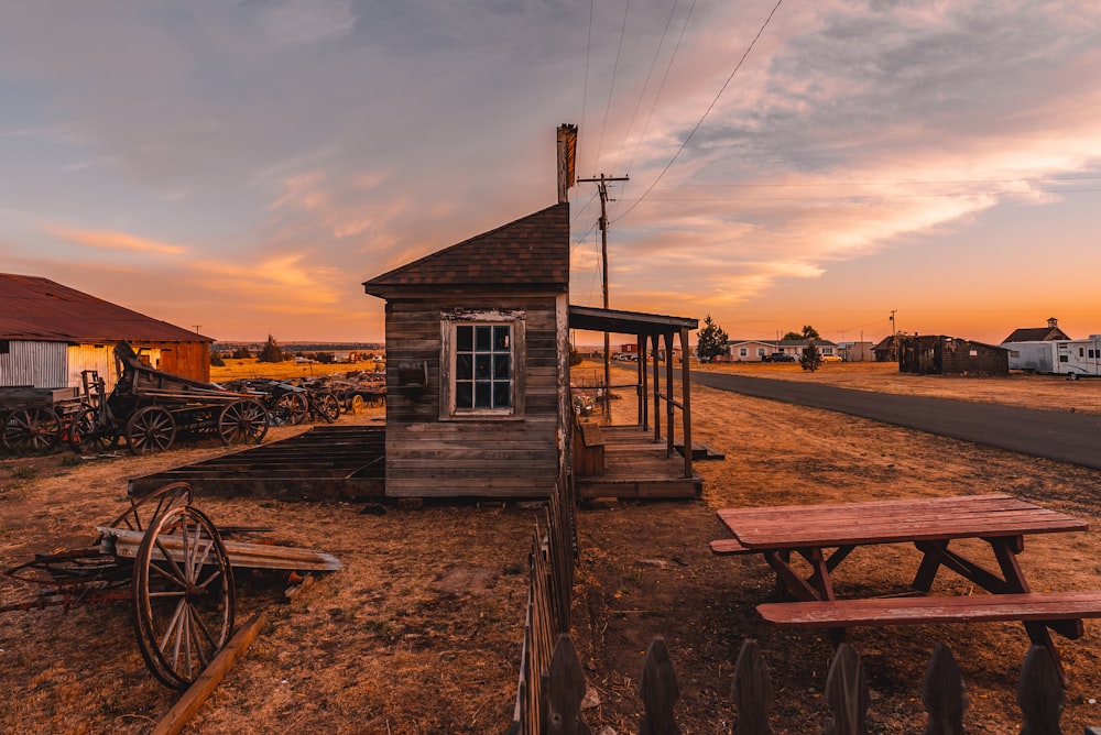 a wooden building with a wheelbarrow and a wooden table