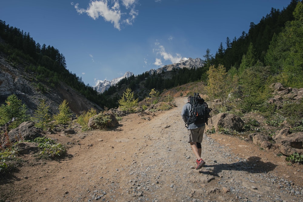 a person walking on a dirt path in the mountains