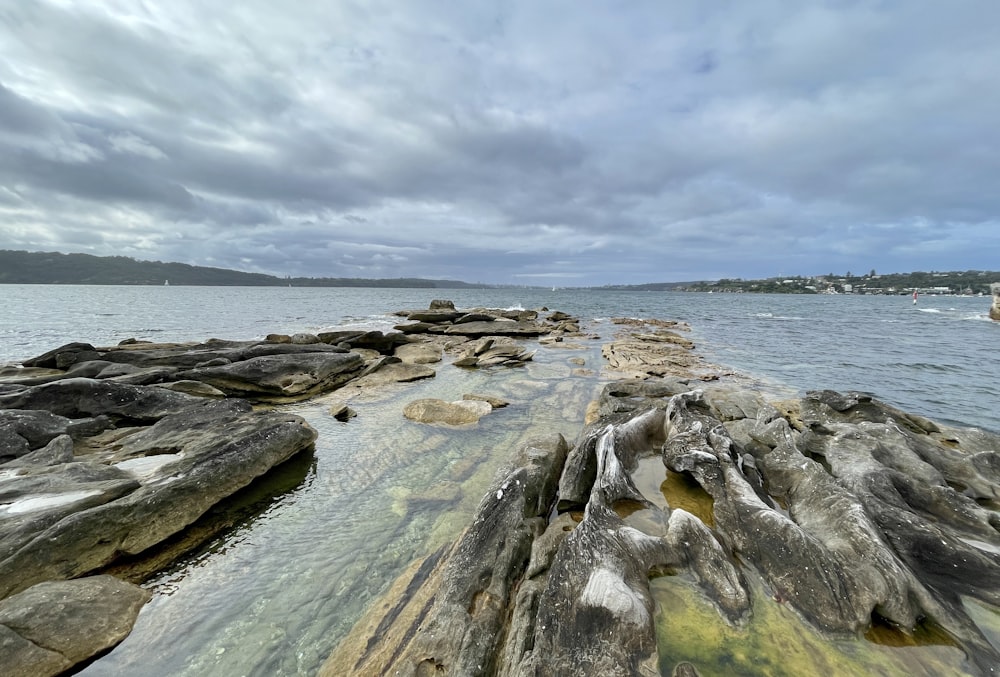 a rocky beach with a body of water in the background