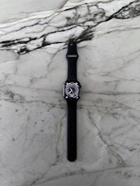 A modern watch with a sleek design on a marble table.