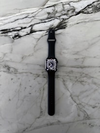Sleek chronograph watch with black leather strap resting elegantly on a white marble surface.