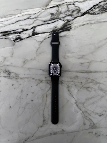 A sleek electric blue smartwatch resting on a marble surface reflecting subtle light.