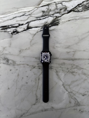 Sleek chronograph watch with black leather strap resting elegantly on a white marble surface.