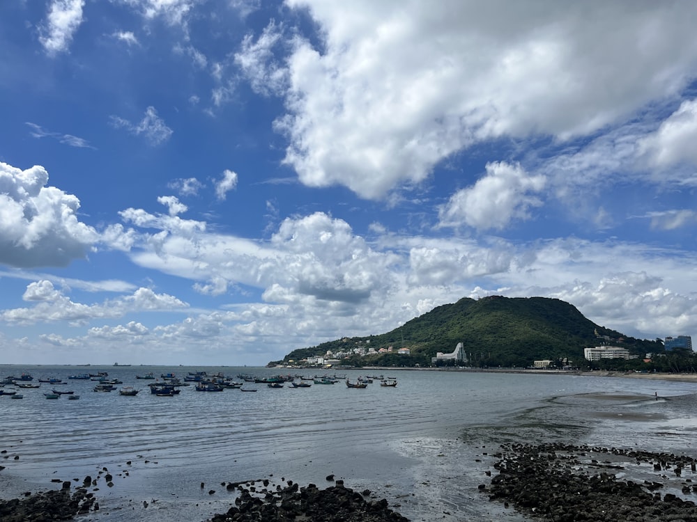 a body of water with boats in it and a hill in the background