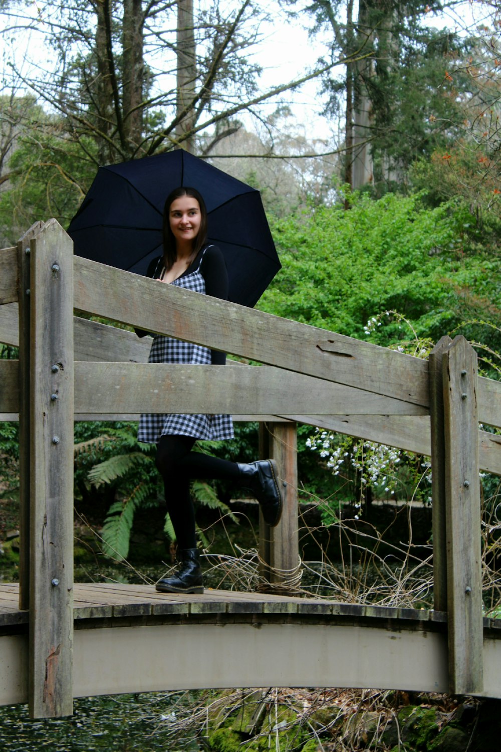 a person sitting on a wooden fence holding an umbrella