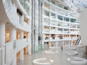 a large white building with white walls and a few people walking around