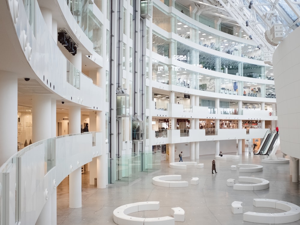 a large white building with white walls and a few people walking around