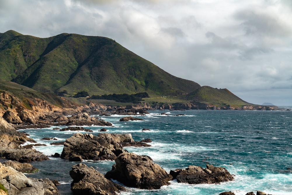 a rocky beach with a large mountain in the background