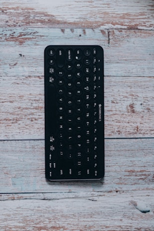 Foldable Bluetooth keyboard stretched out on a wooden picnic table.