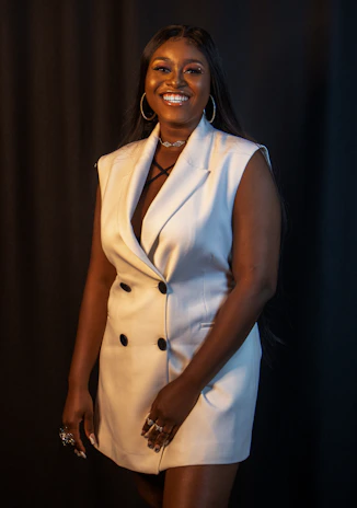 Stylish woman wearing a bernae bracelet, smiling against a dark, luxurious background.